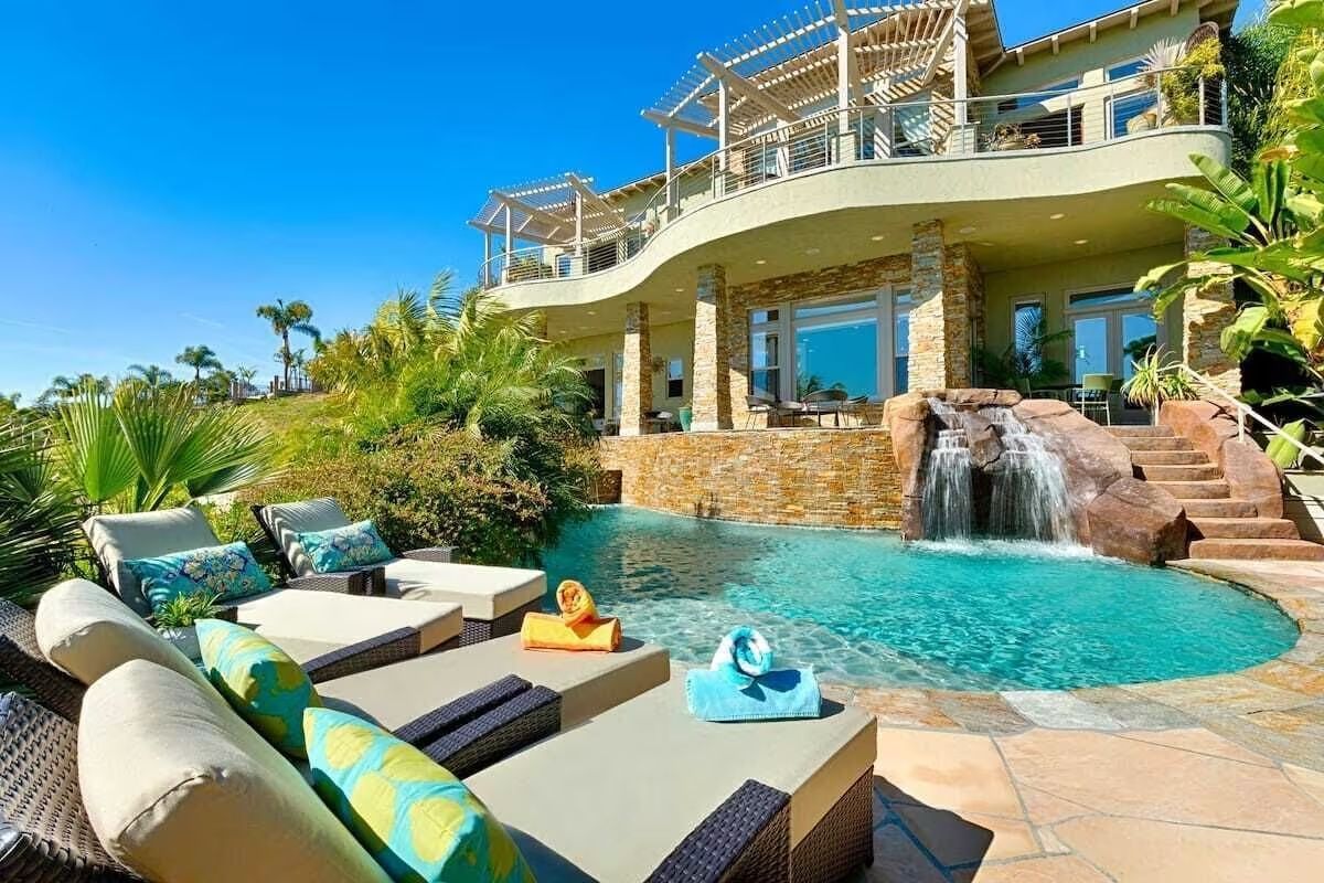 a large house with a swimming pool and a waterfall in the backyard