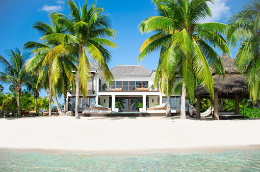 a house on the beach surrounded by palm trees