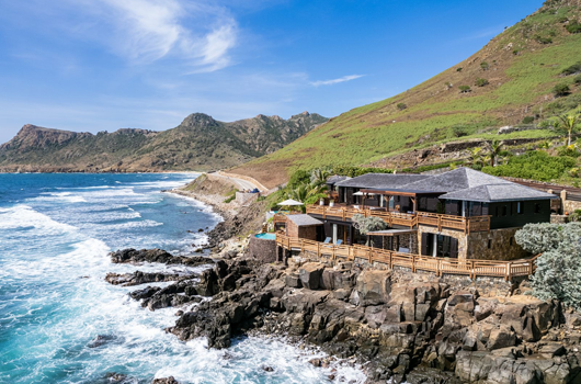 an aerial view of a house on a cliff overlooking the ocean