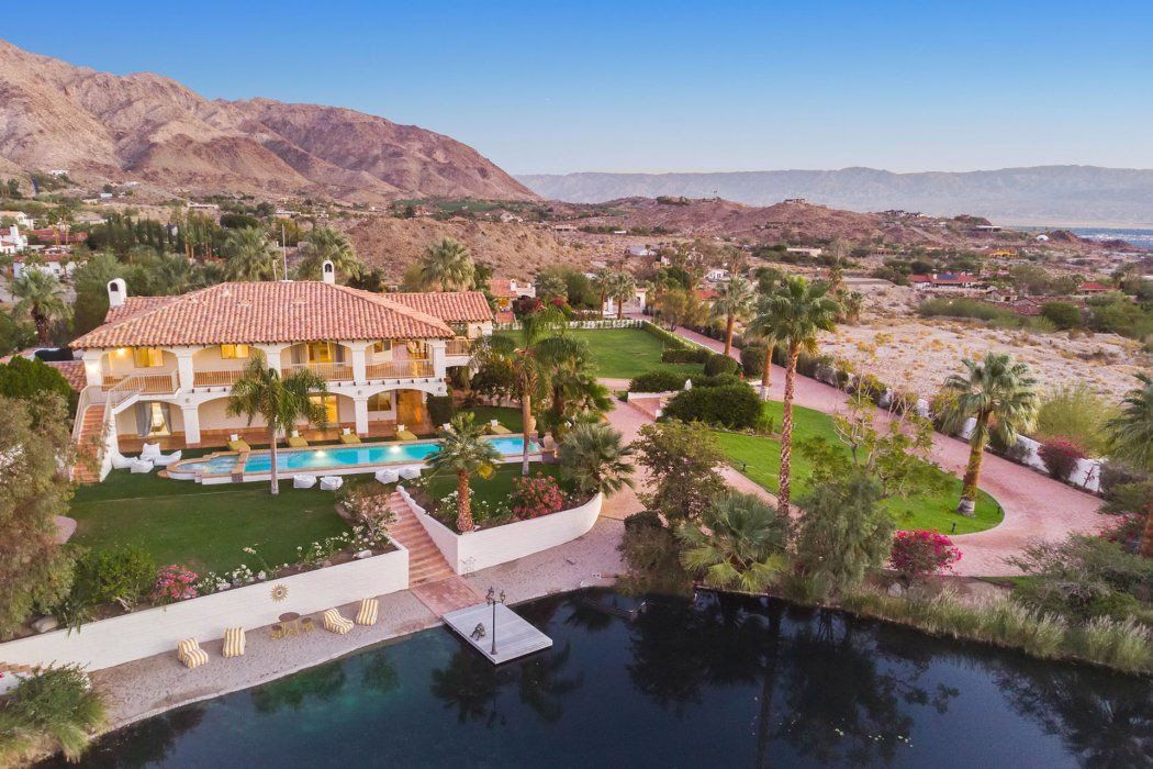 An aerial view of a large house with a pool in front of it.